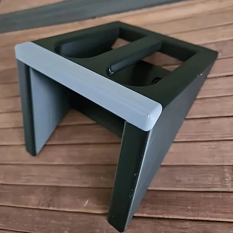 Black punk-style plastic pistol display stand on a surface, showing its compact size and cradle design.