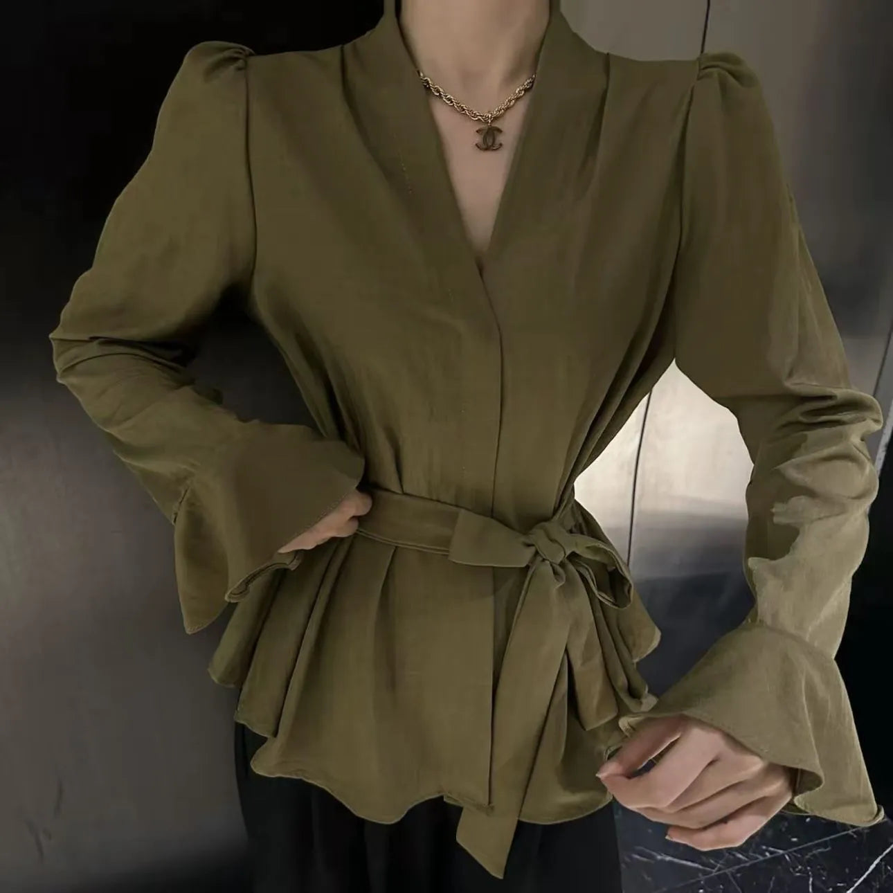 Woman wearing a wine red long sleeve shirt with an irregular French collar, bell sleeves, and a tie front.
