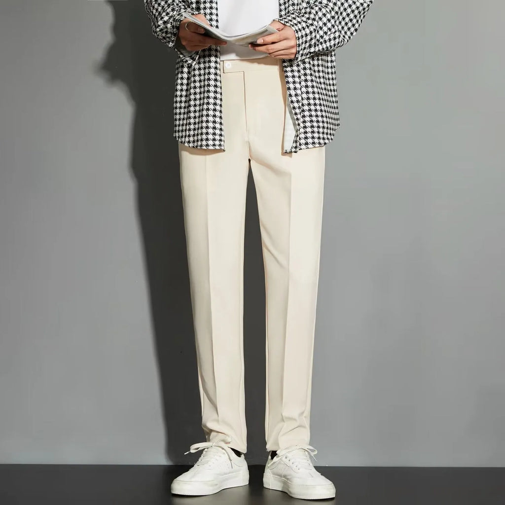 Man wearing straight leg ankle-length suit trousers in a light colour, showing the drape of the fabric.