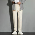 Man wearing straight leg ankle-length suit trousers in a light colour, showing the drape of the fabric.