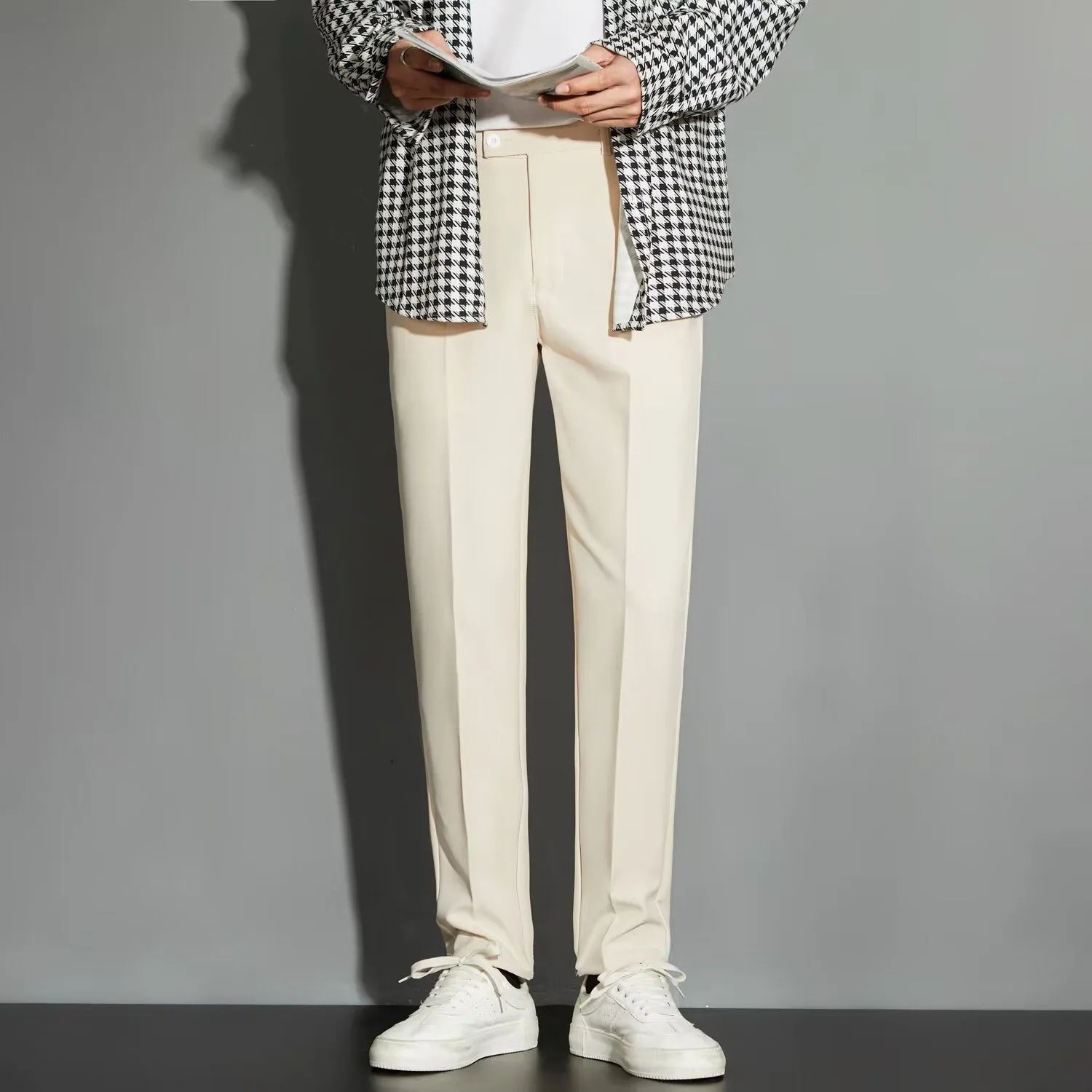 Man wearing straight leg ankle-length suit trousers in a light colour, showing the drape of the fabric.