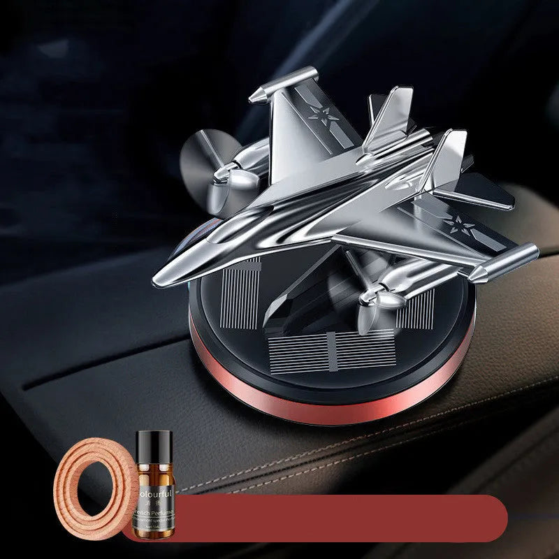 Silver solar powered rotating fighter aircraft perfume ornament on a table.
