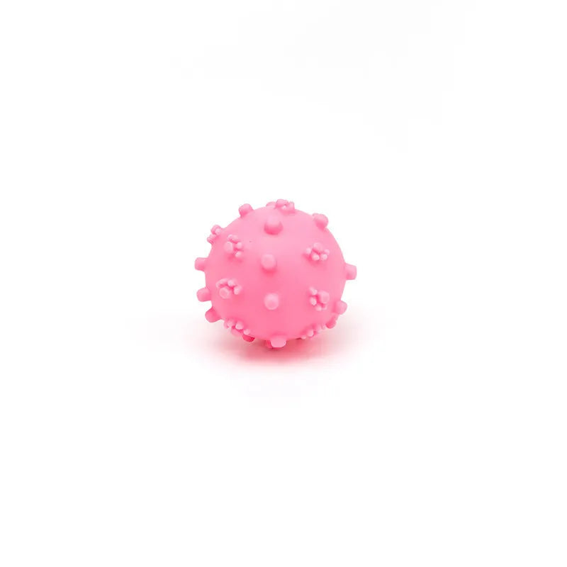 Bright blue, green, pink, and yellow spiked dog toy balls with paw print dimples on a white background.