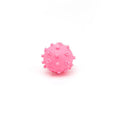 Bright blue, green, pink, and yellow spiked dog toy balls with paw print dimples on a white background.