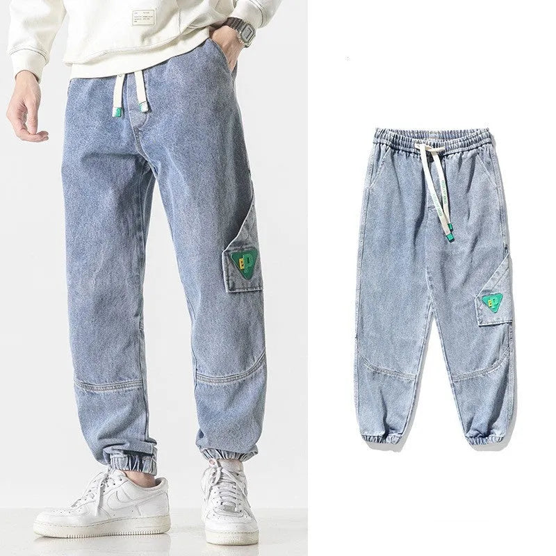 Men's loose fit tapered cotton trousers in black, shown on a model, featuring a mid-waist and tapered leg design.