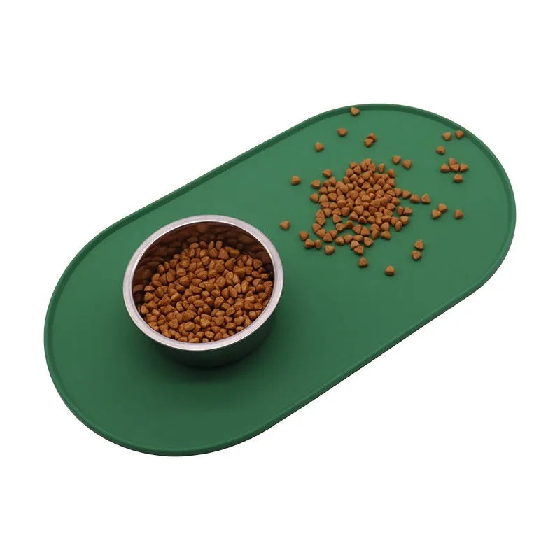 Silicone cat feeding placemat in green colour, shown under a food bowl on a wooden floor.