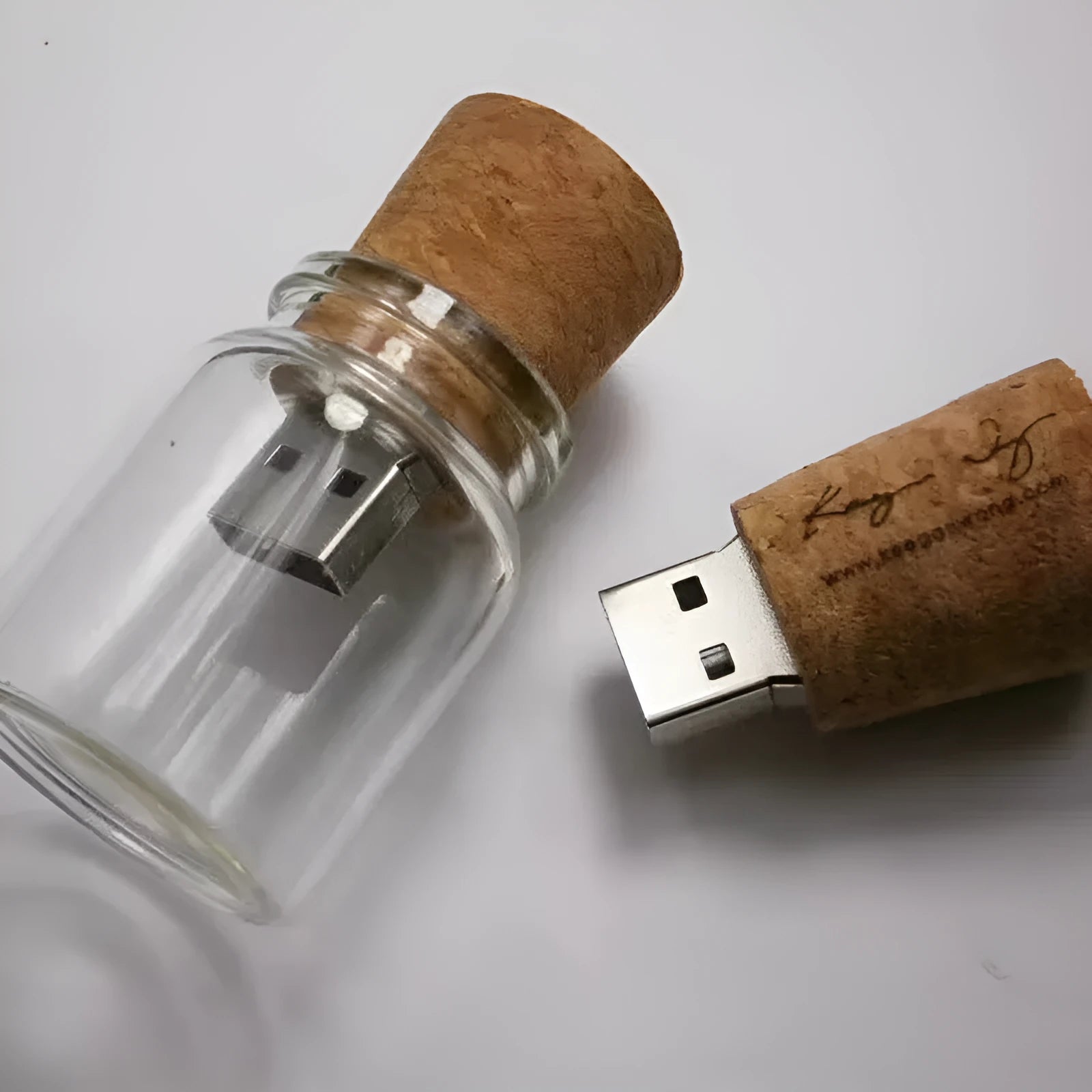 Wooden-capped transparent glass bottle USB flash drive on a wooden surface.