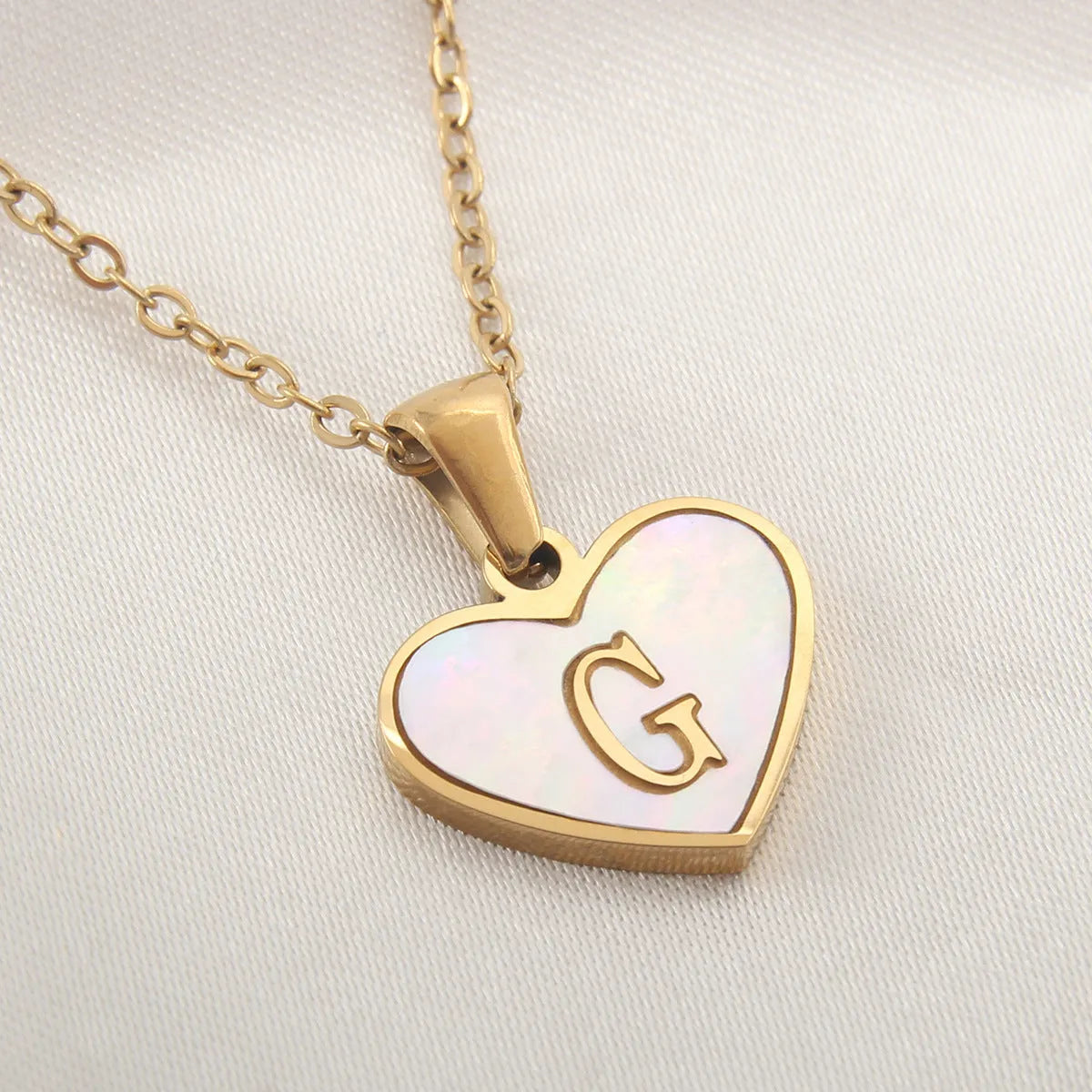 Gold-plated heart necklace with white shell pendant personalised with a letter, on an adjustable chain.