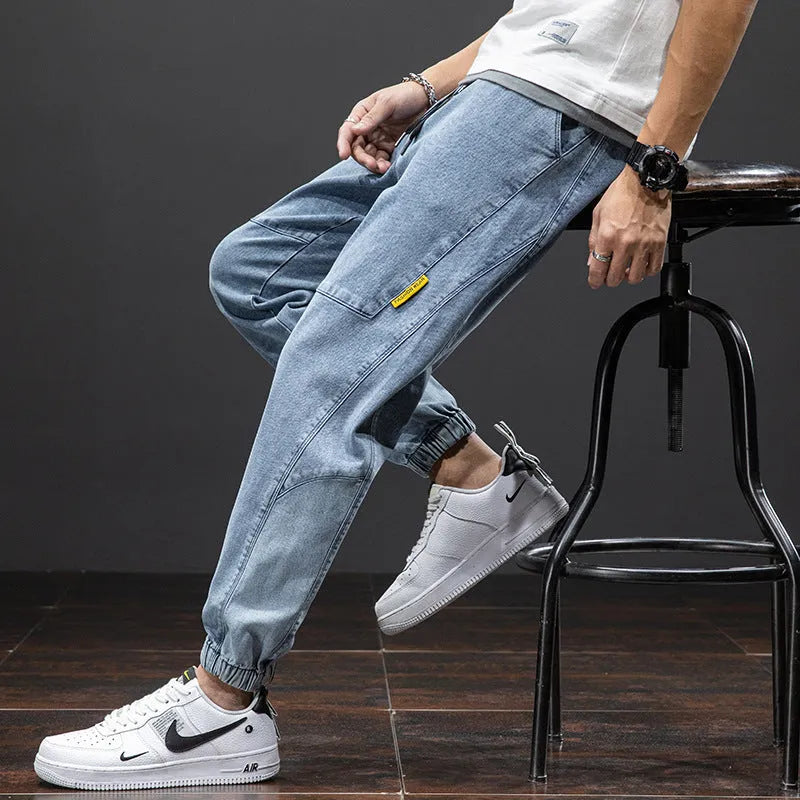 Man wearing loose fit straight leg cargo jeans in blue, showing zipper fly and cargo pocket detail.