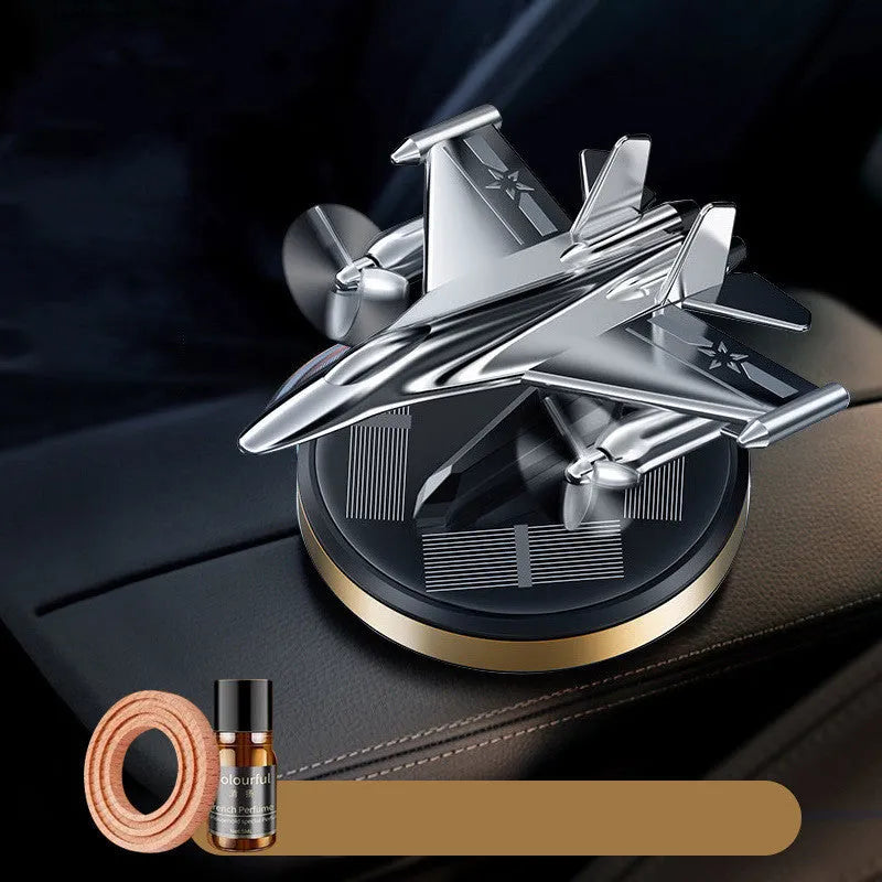 Silver solar powered rotating fighter aircraft perfume ornament on a table.