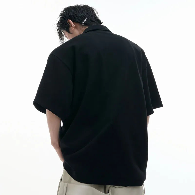 Men's black polo shirt with a deconstructed collar and geometric pattern, loose fit.