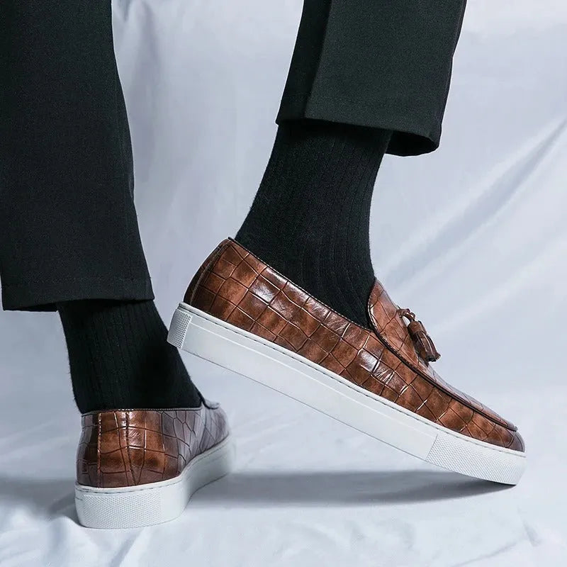 Men's black tassel detail slip-on sneakers on a white background, showing the round toe and elastic side.