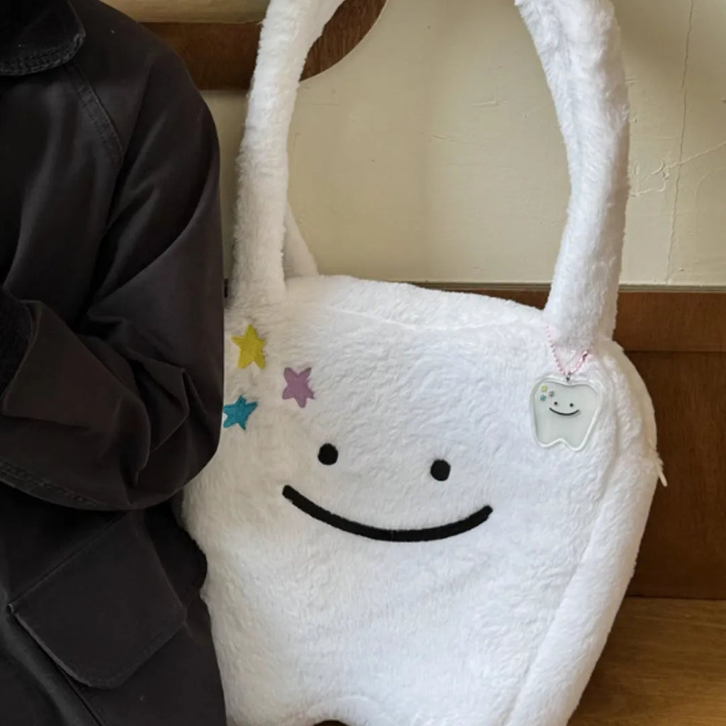 White shoulder tote bag with plush large tooth decorative detail and zip closure