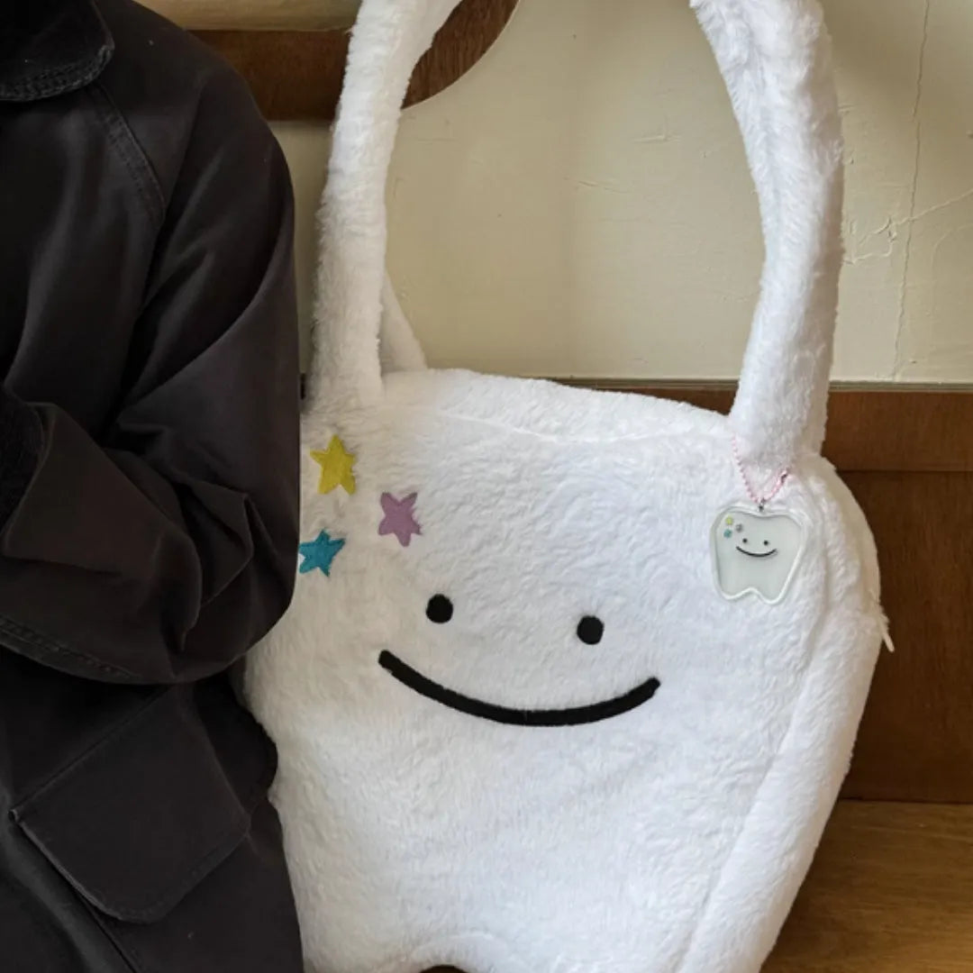 White shoulder tote bag with plush large tooth decorative detail and zip closure