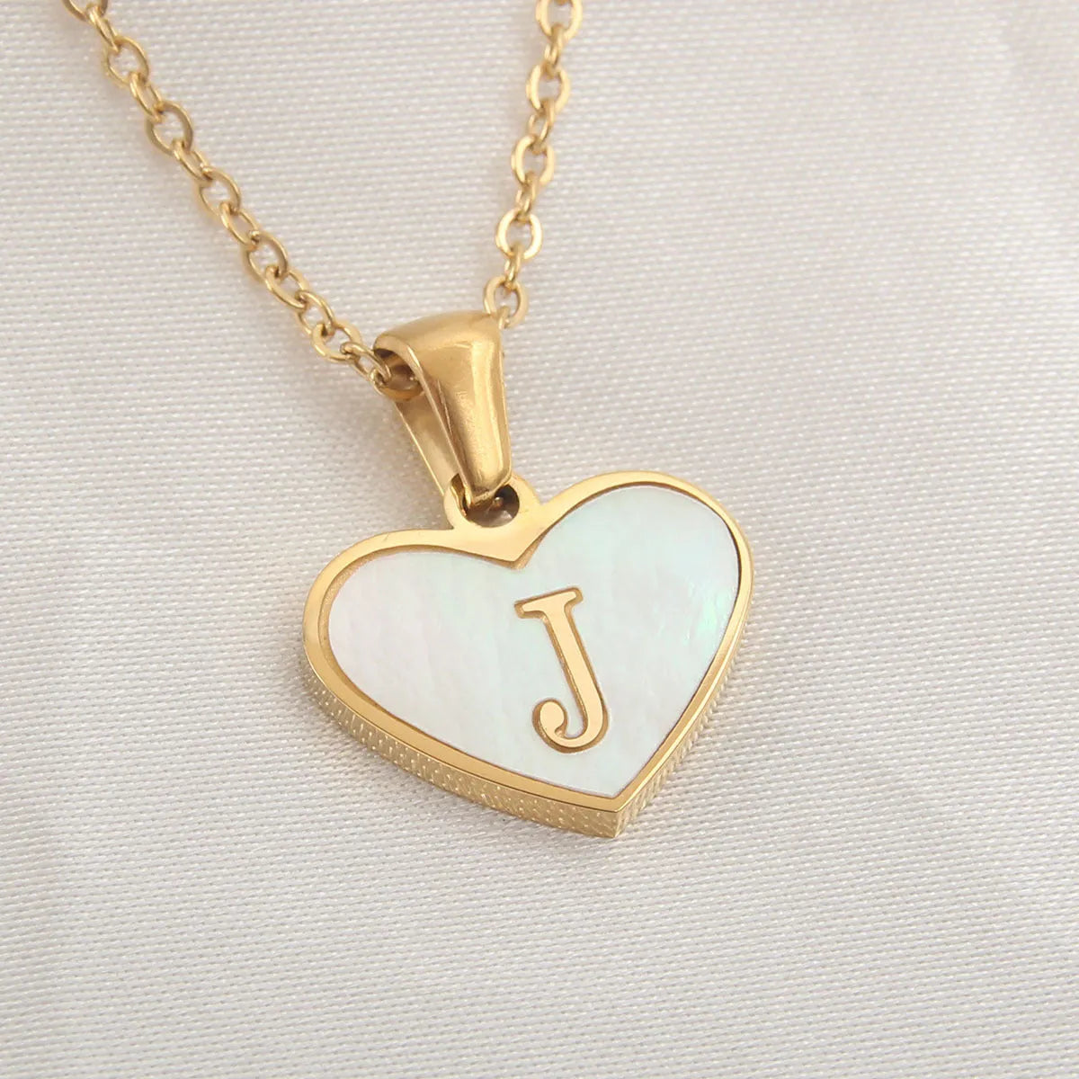 Gold-plated heart necklace with white shell pendant personalised with a letter, on an adjustable chain.