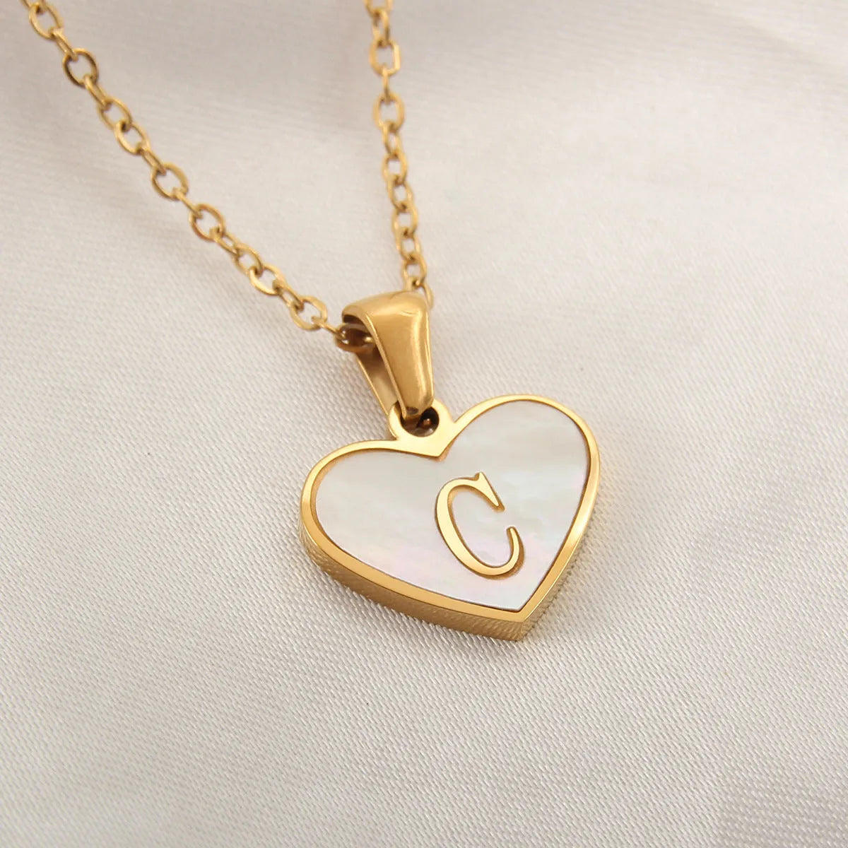 Gold-plated heart necklace with white shell pendant personalised with a letter, on an adjustable chain.