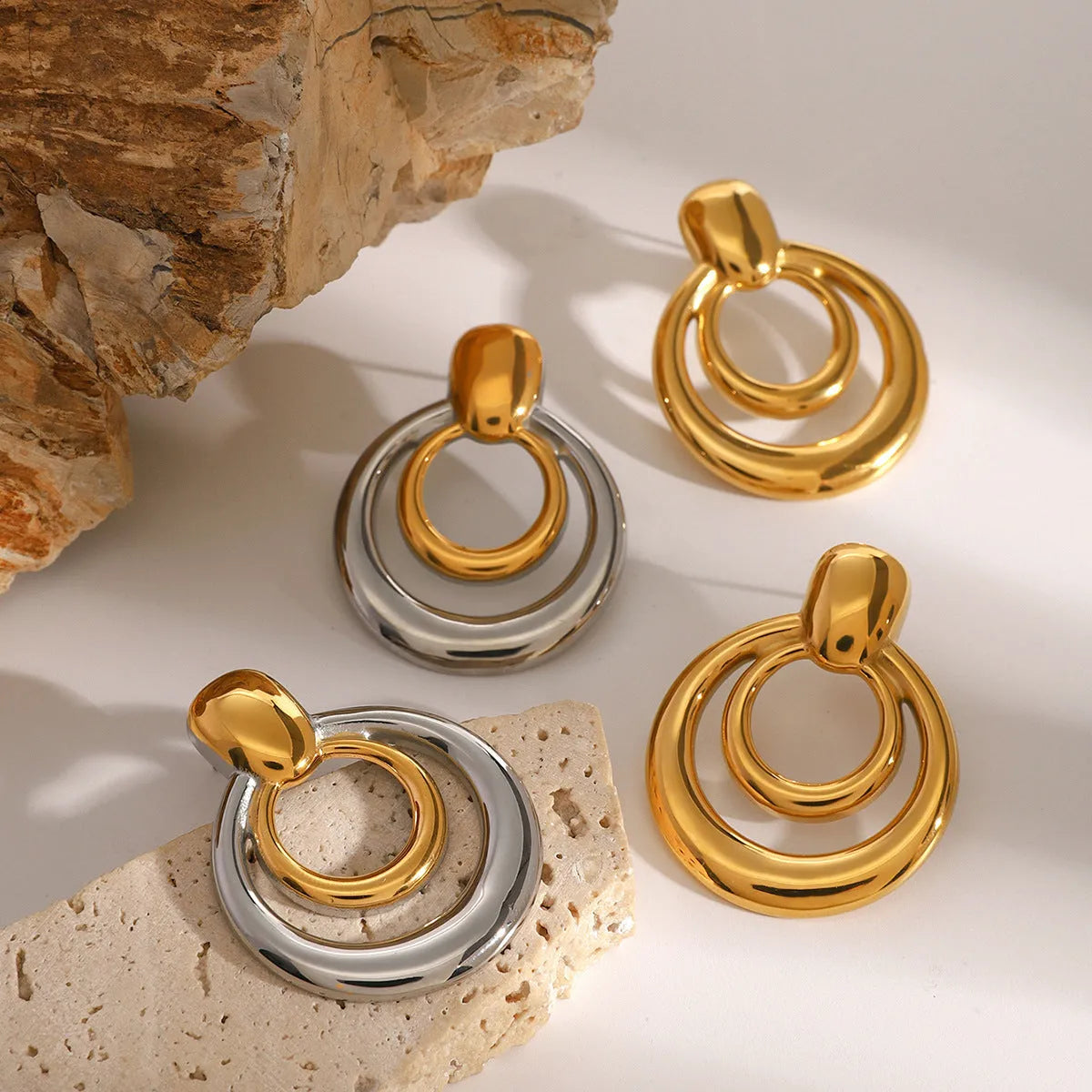Round double layer hollow stud earrings with a gold electroplated finish on a titanium steel base.
