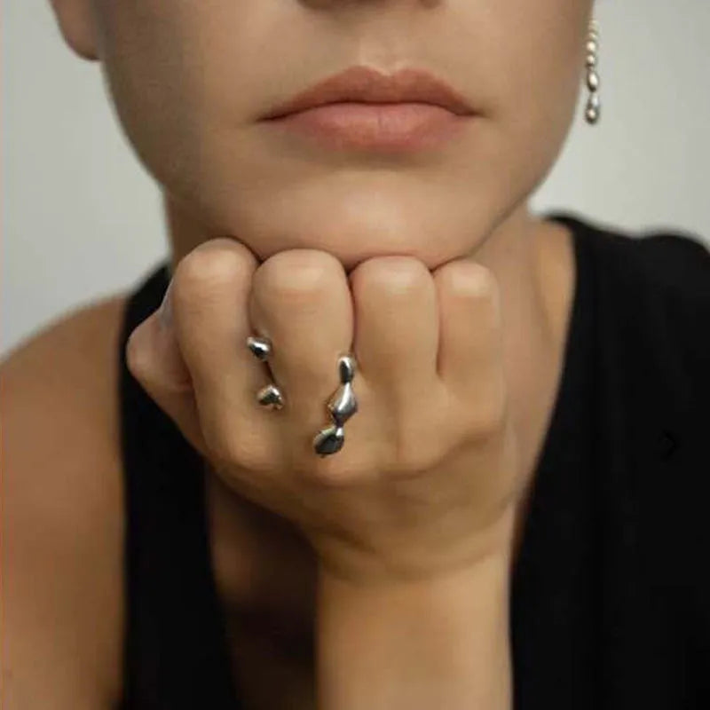Gold or silver brass opening ring with spherical design elements on a model's finger.