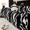 Thickened flannel zebra pattern sofa cover in caramel or black draping over a sofa with non-slip texture visible