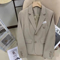 Women's black loose-fit short suit coat with long sleeves and pocket details.