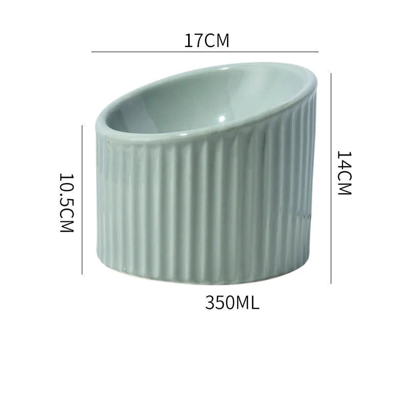 Dark green elevated ceramic cat bowl on a wooden floor, showing its raised height and round, whisker-friendly shape.