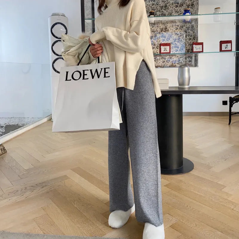 Woman wearing high waist cream white knitted wide-leg trousers with a straight, drooping mopping cut.