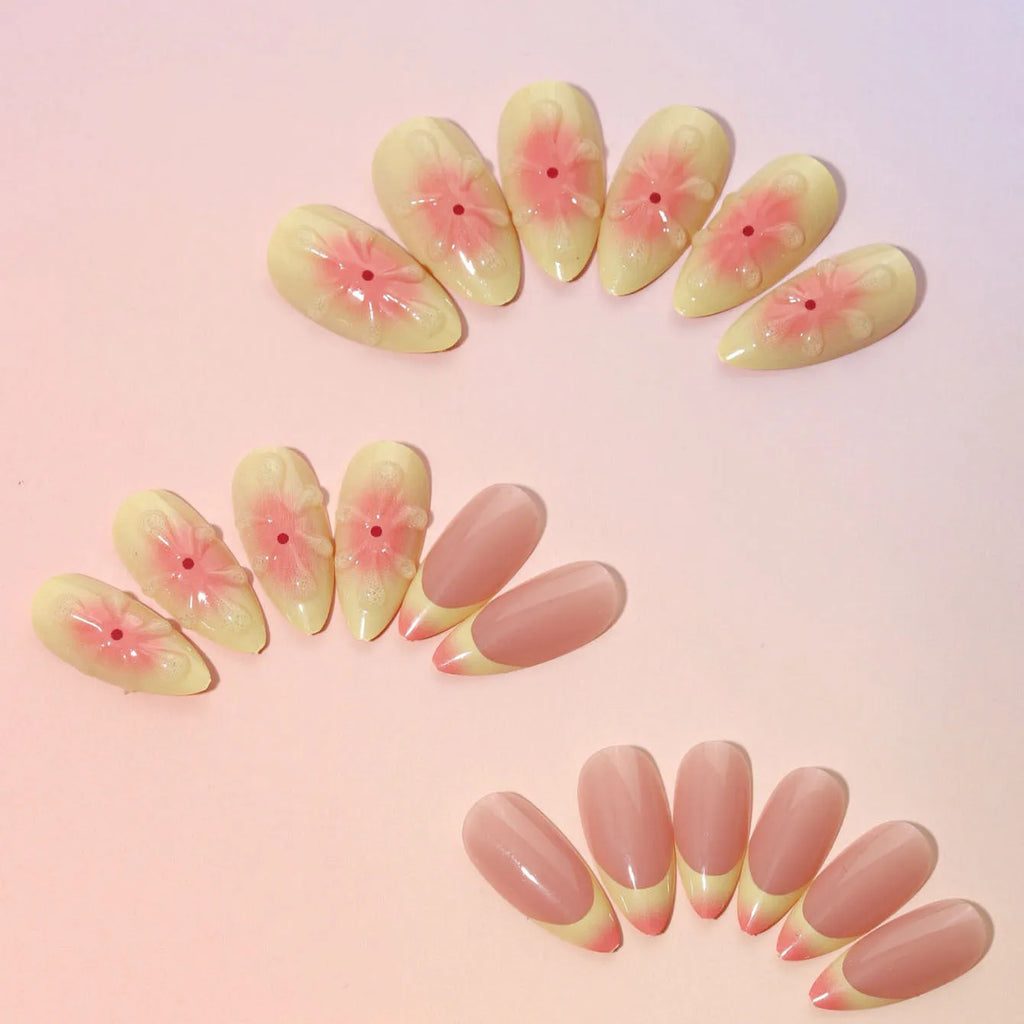 Set of plastic detachable fake nails with pink and white 3D cartoon flower designs, pot of jelly glue, and a nail file.