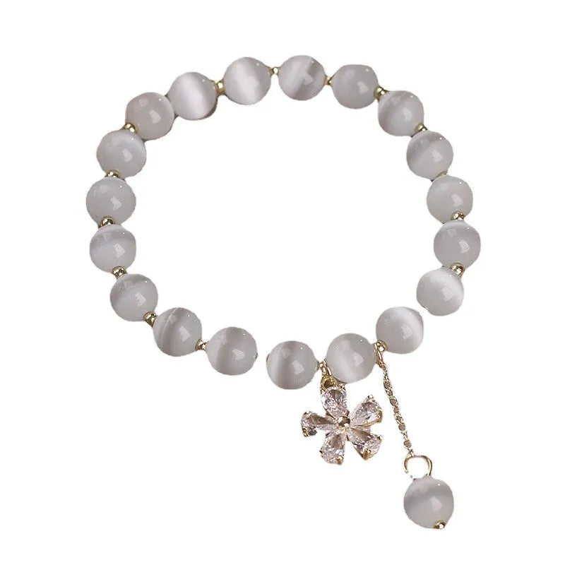 Women's single loop white cat's eye crystal bracelet with flower tassel and morganite safety buckle pendant.
