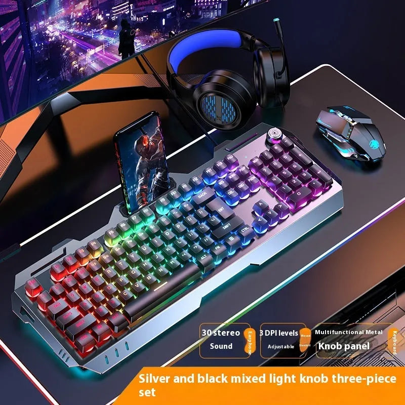Aluminium gaming keyboard with volume knob, shown in metal grey with RGB lighting alongside optional macro mouse and headset.