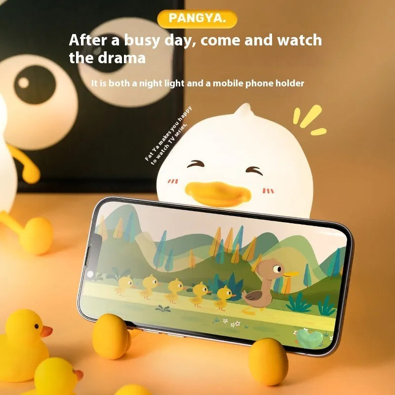 Chubby silicone pat night light on a desk holding a mobile phone, showing its compact size and soft design.