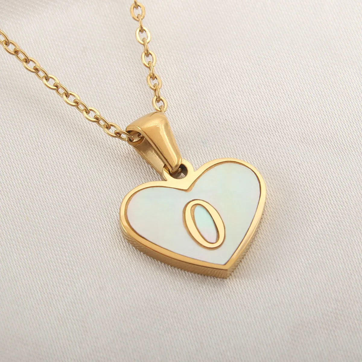 Gold-plated heart necklace with white shell pendant personalised with a letter, on an adjustable chain.