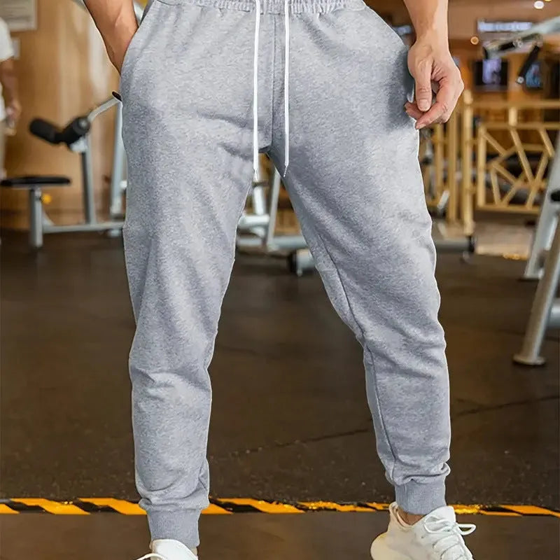 Men's loose fit linen-style trousers with a drawstring elastic waist, shown in a casual setting.
