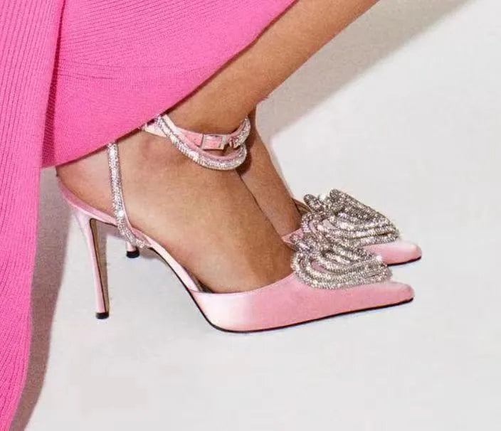 Women's pink satin sandals with heart-shaped rhinestone detail and cross-band straps on a pointed toe.