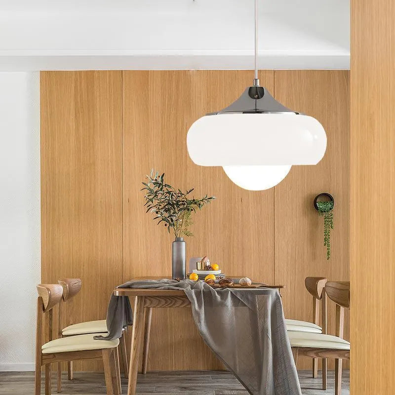 Three-headed Bauhaus pendant light with milky white glass egg tart shades hanging from a ceiling.