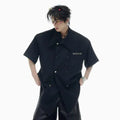 Men's loose casual short-sleeved summer shirt in black with splicing detail and metal buttons.
