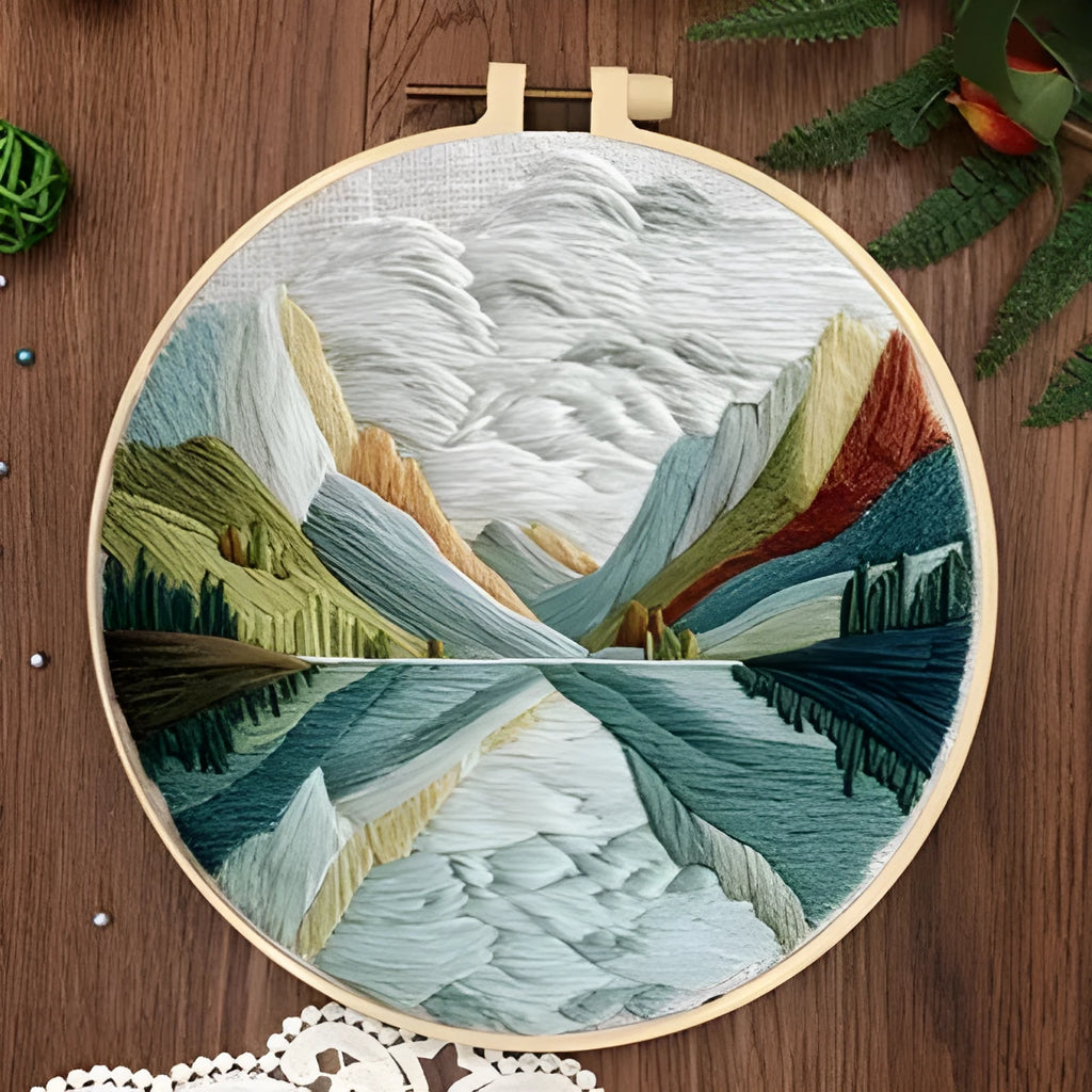 DIY landscape embroidery kit with cotton fabric, bamboo frame, threads and needles arranged for crafting