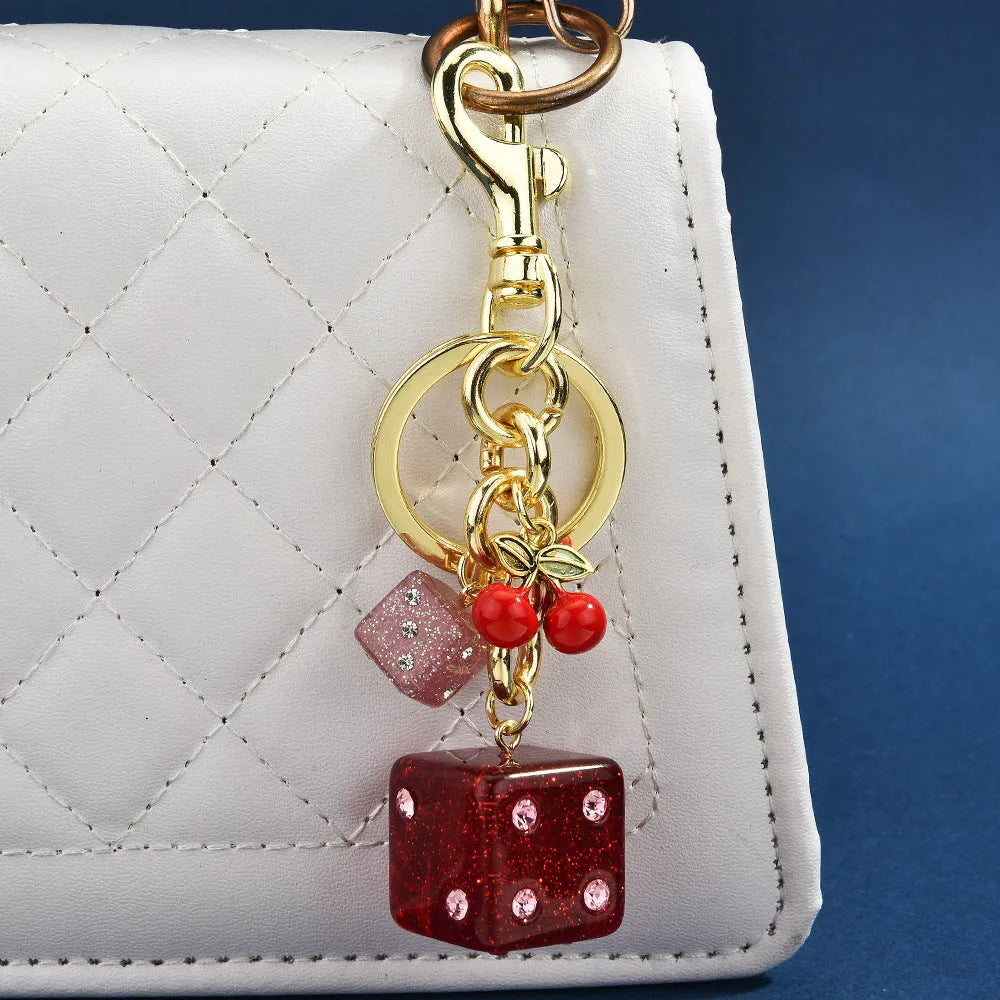 Square metal keychain pendant with a vintage two-tone cherry dice pattern on a white background.