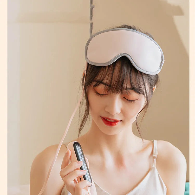 Pink and green portable eye SPA massage goggles showing USB port and suede exterior.