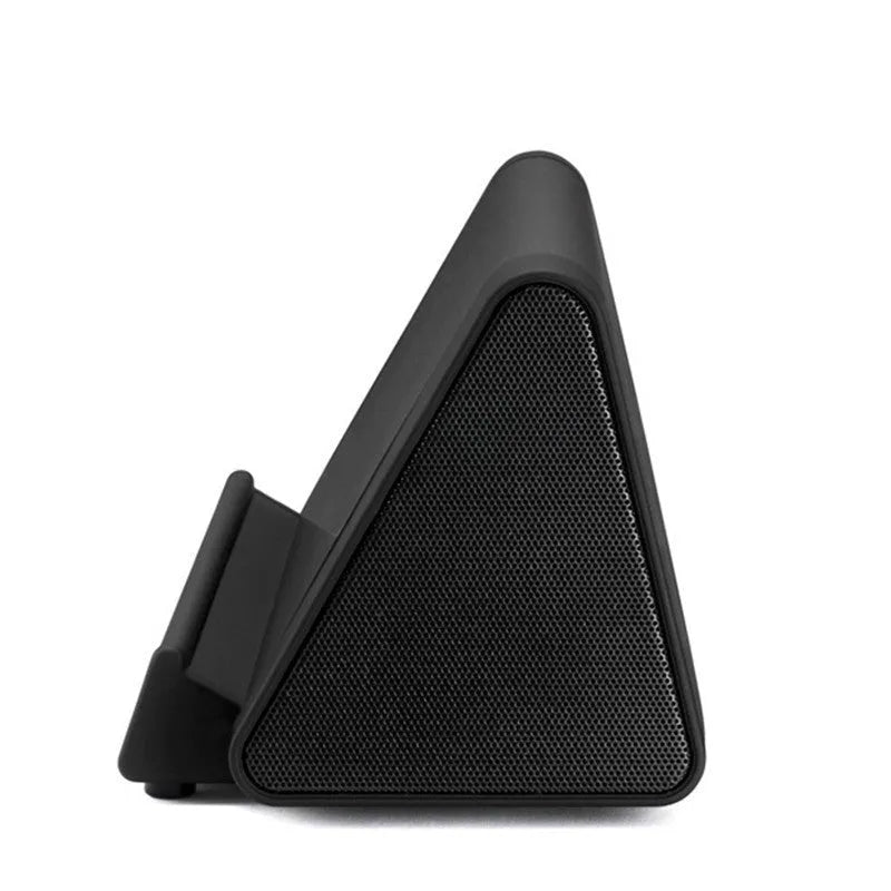 Small black and white wireless Bluetooth speaker with built-in USB charging cable on a desk.