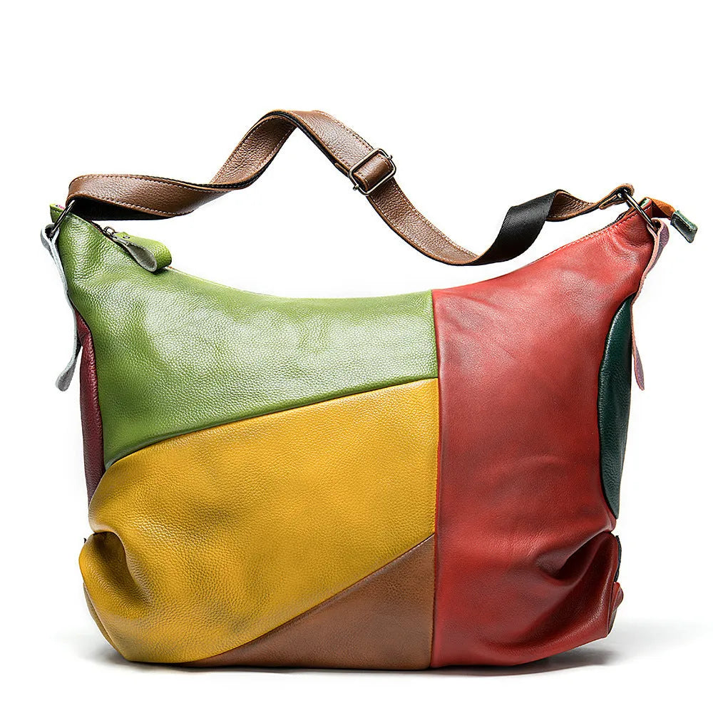 Brown cowhide leather crossbody travel bag with stitching detail, shown with a laptop and magazine.