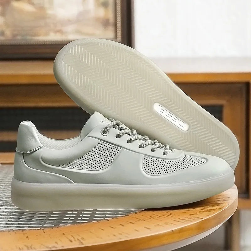 white perforated leather casual training shoes with rubber sole and front lace-up on flat surface
