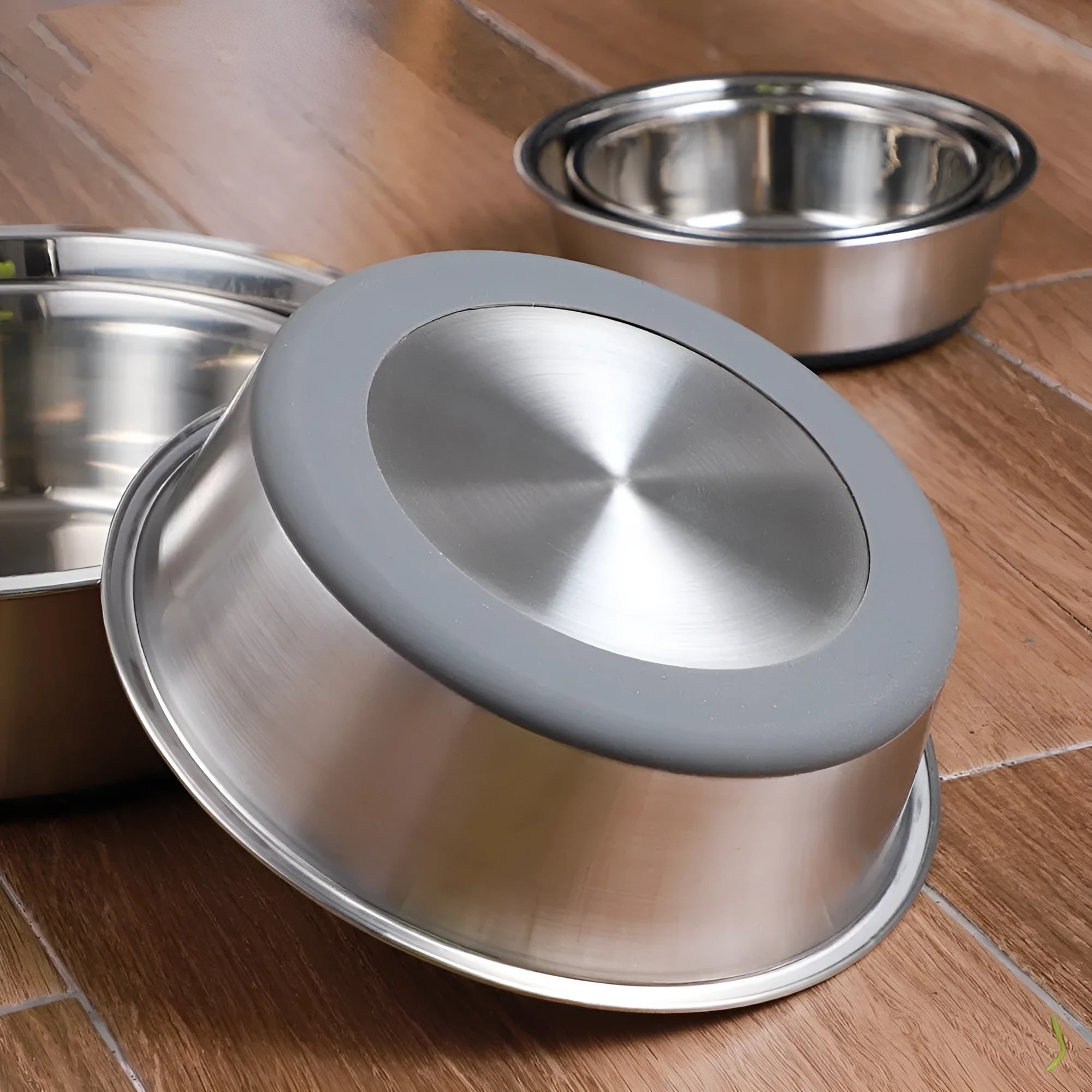 Silicone pet bowl with stainless steel interior in black, shown on floor with anti-slip ring around base