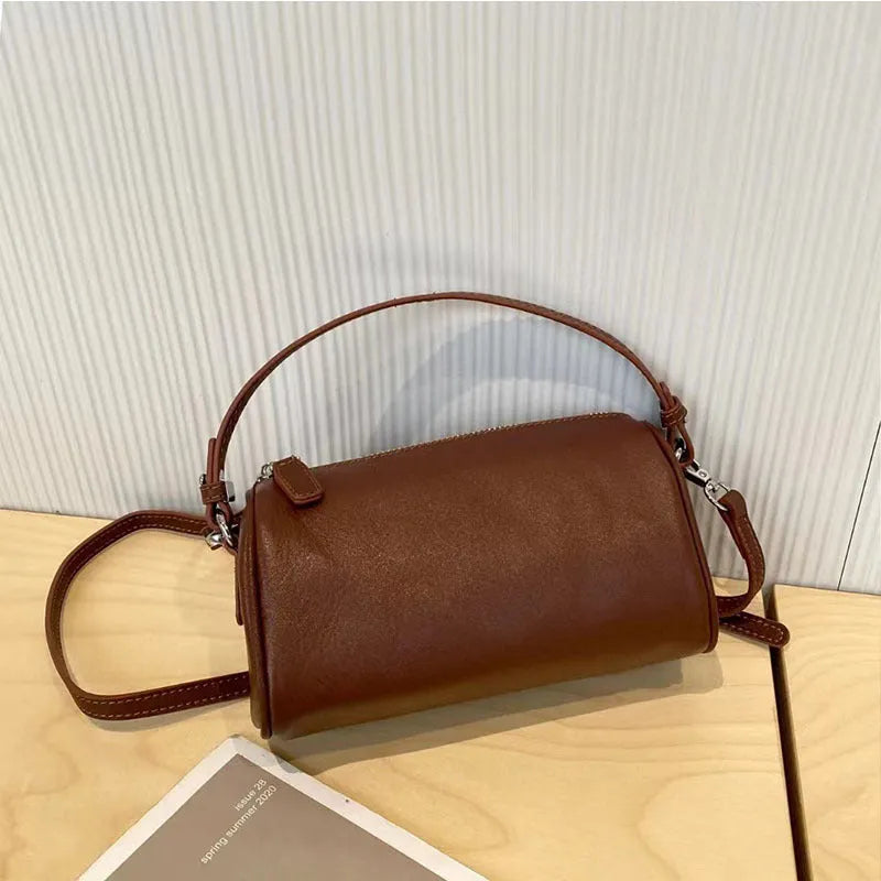 Soft genuine leather cylindrical crossbody bag for mobile phones, shown in a street style with visible stitching.