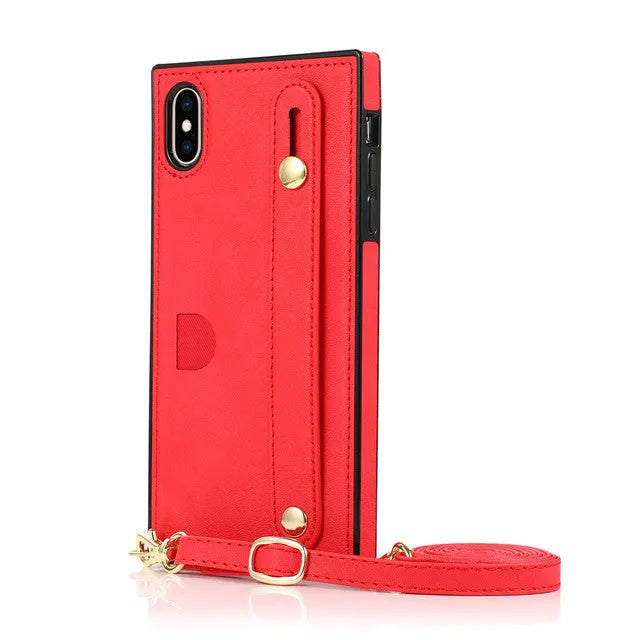 Black leather iPhone case with card holder slot and detachable wrist strap on a table
