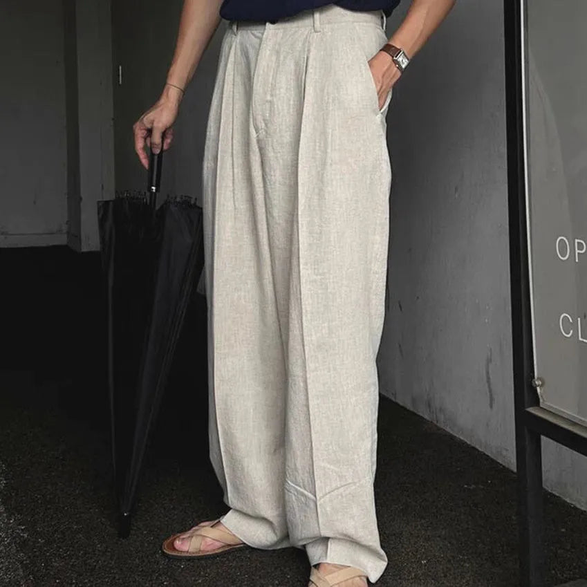 Men's lightweight apricot coloured wide-leg cotton linen trousers with a pencil leg opening on a hanger