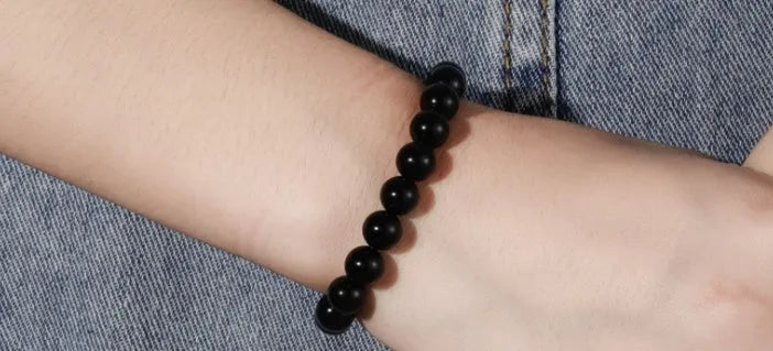 A geometric black onyx bracelet for women with 8mm beads on an elastic cord.