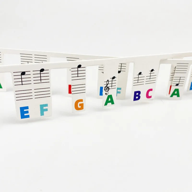 Two bags of white card piano keyboard stickers for 88 keys, showing colour note bar and black note designs.