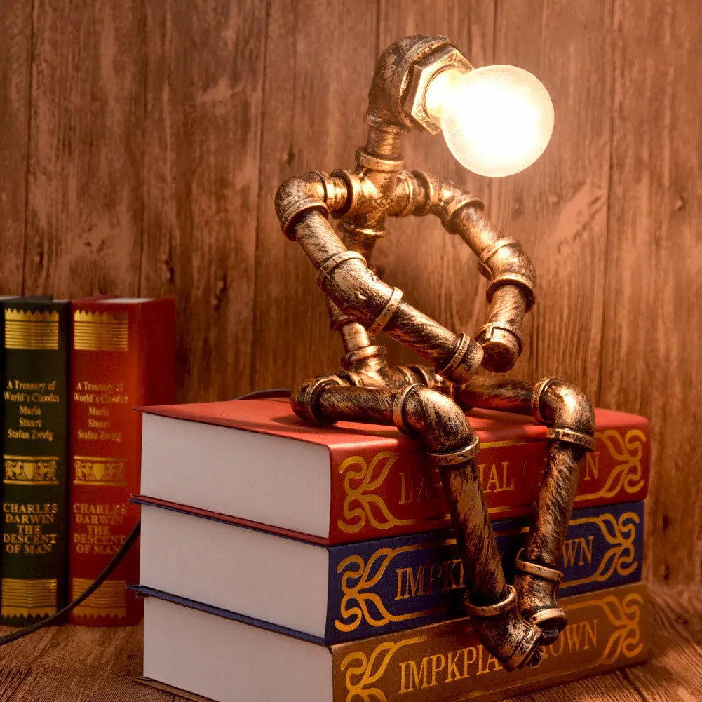 Green bronze vintage robot table lamp with industrial iron pipe design on wooden desk