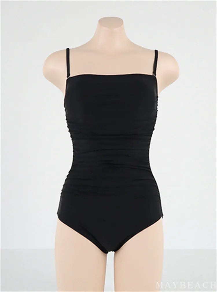 Sling style one-piece swimsuit with belly pleating in a solid colour.