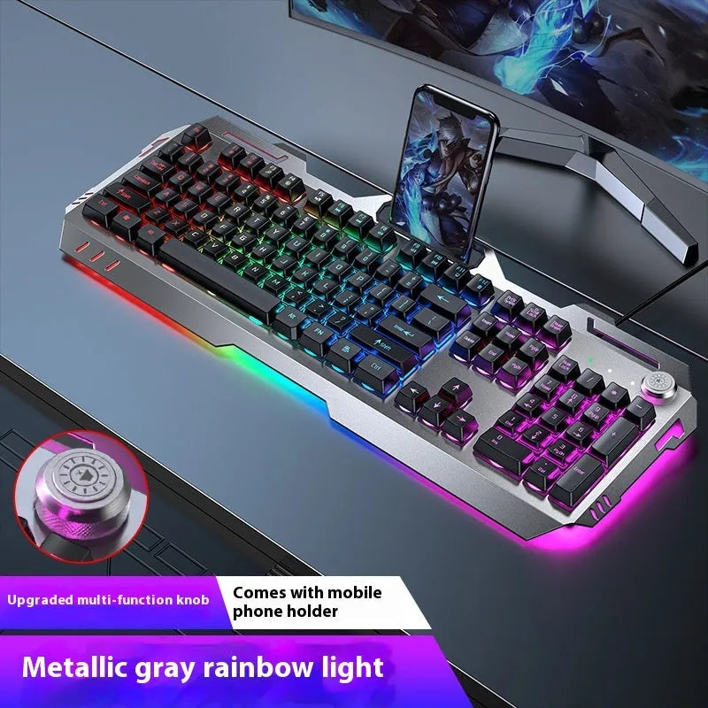 Aluminium gaming keyboard with volume knob, shown in metal grey with RGB lighting alongside optional macro mouse and headset.